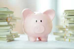 piggy bank surrounded by stacks of dollar bills from a rental property