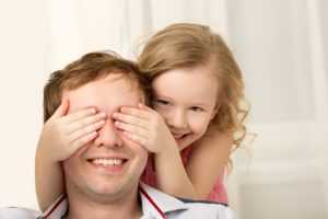 Little daughter closing dads eyes with hands and laughing after child custody case